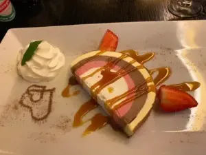Leckeres Dessert auf weißem Teller, dekoriert mit Sahne und saftigen Erdbeeren.